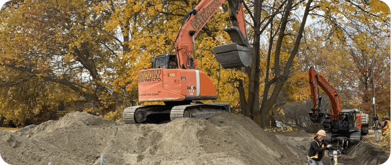 Two excavators operate on a dirt pile, showcasing construction activity and heavy machinery in action