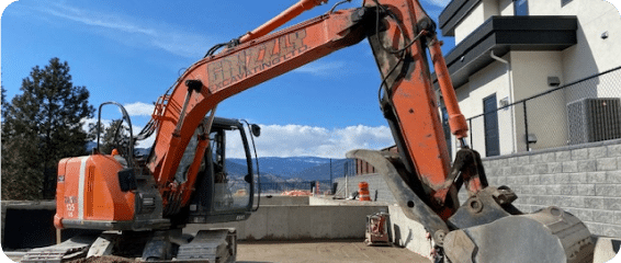 An orange excavator operates on a construction site, digging and moving materials for building development