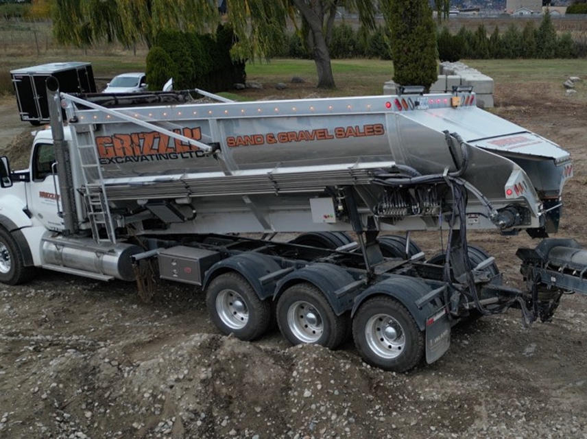 A dump truck with a large bed parked on the roadside, ready for loading or unloading materials